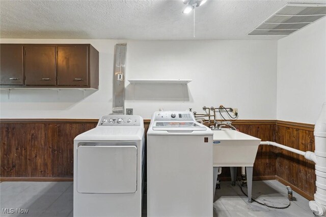 3917 Oxford Dr, Lorain, OH 44053 - laundry area featuring separate washer and dryer, a wainscoted wall, wooden walls, a textured ceiling, and cabinet space