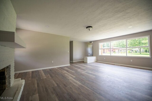4029 Minard Rd NW, Dover, OH 44622 - unfurnished living room with wood finished floors, a fireplace with raised hearth, and a textured ceiling