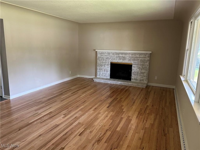 7295 Clovermeade Ave, Poland, OH 44514 - unfurnished living room featuring wood finished floors, a stone fireplace, and baseboard heating