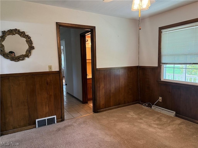 3022 Heatherbrae Dr, Poland, OH 44514 - empty room featuring a wainscoted wall, wooden walls, light colored carpet, a baseboard heating unit, and light tile patterned floors