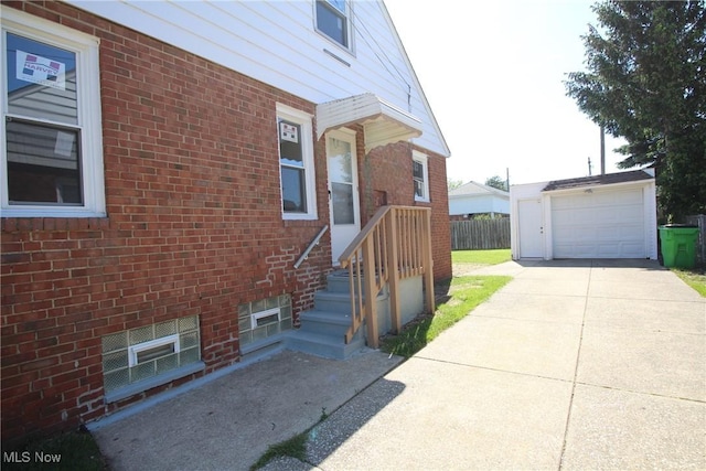 230 E 242nd St, Euclid, OH 44123 - view of side of home with an outdoor structure, concrete driveway, and brick siding