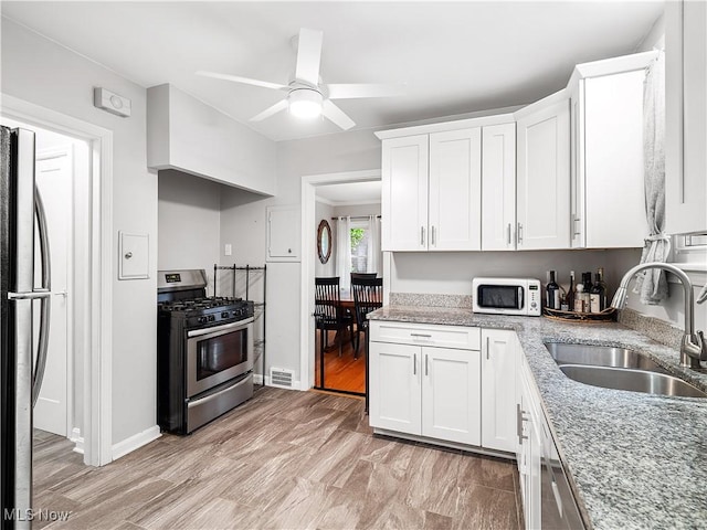 3845 Hillbrook Rd, University Heights, OH 44118 - kitchen featuring stainless steel appliances, white cabinets, light stone countertops, a ceiling fan, and light wood-style flooring
