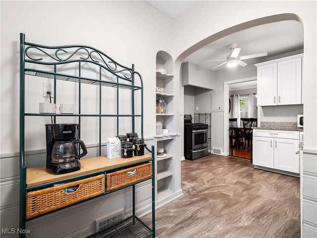 3845 Hillbrook Rd, University Heights, OH 44118 - kitchen featuring stainless steel range with gas cooktop, a ceiling fan, arched walkways, and white cabinetry
