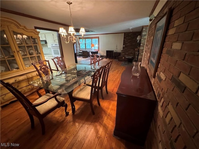 9999 Kirtland Chardon Rd, Chardon, OH 44024 - dining area with hardwood / wood-style floors, crown molding, a chandelier, and brick wall