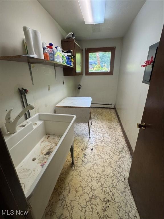 9999 Kirtland Chardon Rd, Chardon, OH 44024 - laundry area featuring a baseboard heating unit, light stone finish floors, and cabinet space