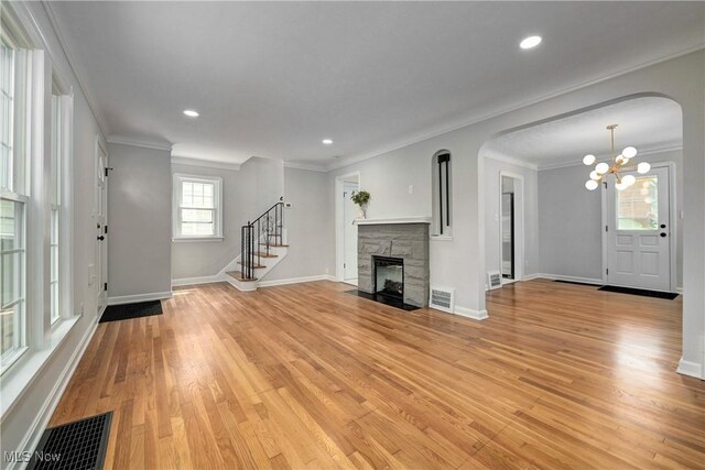 17631 Milburn Ave, Cleveland, OH 44135 - unfurnished living room with a chandelier, light wood-style flooring, crown molding, a stone fireplace, and stairs