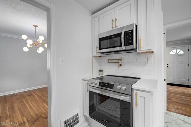 17631 Milburn Ave, Cleveland, OH 44135 - kitchen with appliances with stainless steel finishes, crown molding, light countertops, decorative backsplash, and a chandelier