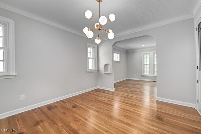 17631 Milburn Ave, Cleveland, OH 44135 - spare room featuring arched walkways, ornamental molding, light wood-style floors, and a chandelier