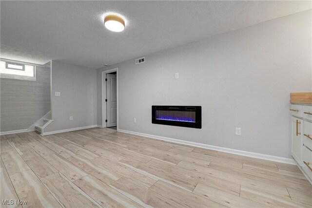 17631 Milburn Ave, Cleveland, OH 44135 - unfurnished living room with a glass covered fireplace, light wood-style floors, and a textured ceiling