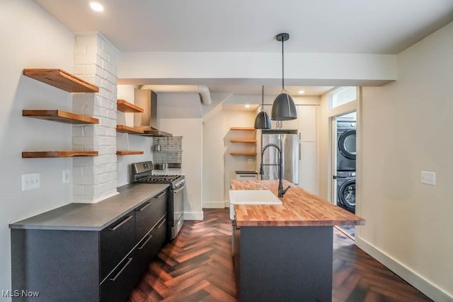 1004 Clarendon Ave SW, Canton, OH 44710 - kitchen featuring stainless steel appliances, open shelves, stacked washer and clothes dryer, wall chimney range hood, and butcher block counters
