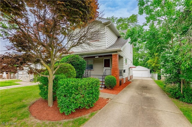 9711 Plymouth Ave, Cleveland, OH 44125 - view of front of home with an outbuilding, covered porch, a garage, a front lawn, and brick siding