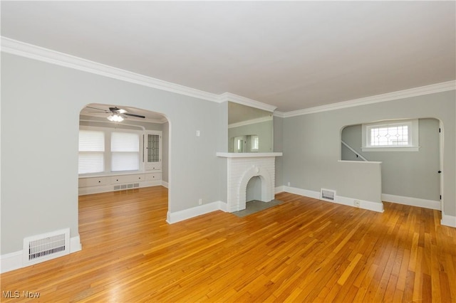 9711 Plymouth Ave, Cleveland, OH 44125 - unfurnished living room with arched walkways, light wood finished floors, ornamental molding, ceiling fan, and a brick fireplace