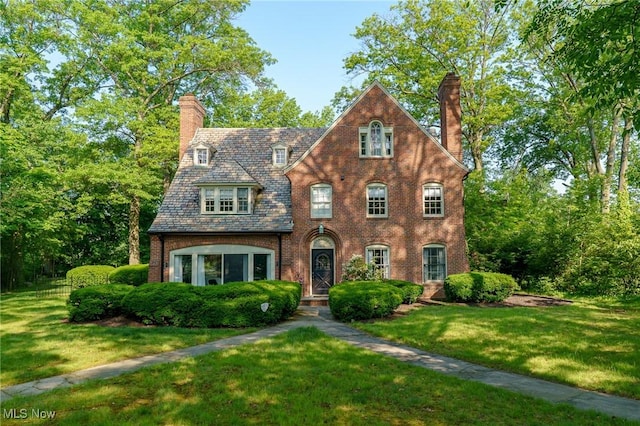 17805 Van Aken Blvd, Shaker Heights, OH 44122 - tudor house with a chimney, a high end roof, a front lawn, and brick siding