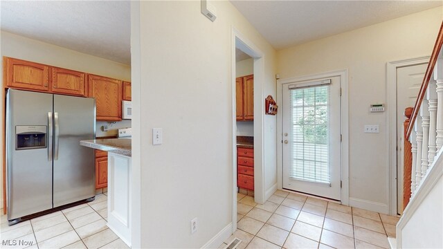 44 Gullybrook Ln, Willoughby, OH 44094 - kitchen featuring stainless steel fridge, light tile patterned floors, white microwave, and brown cabinetry