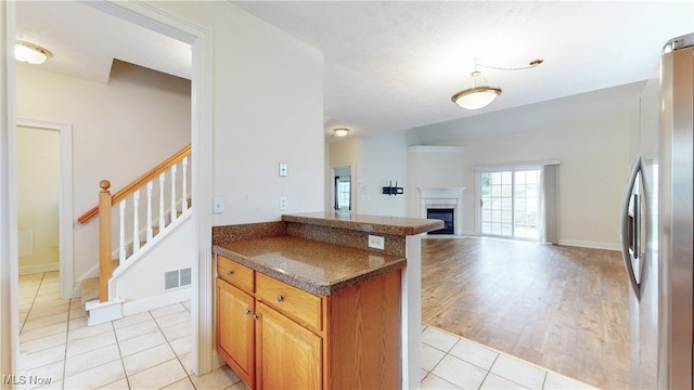 44 Gullybrook Ln, Willoughby, OH 44094 - kitchen featuring freestanding refrigerator, open floor plan, light tile patterned flooring, a fireplace, and a peninsula