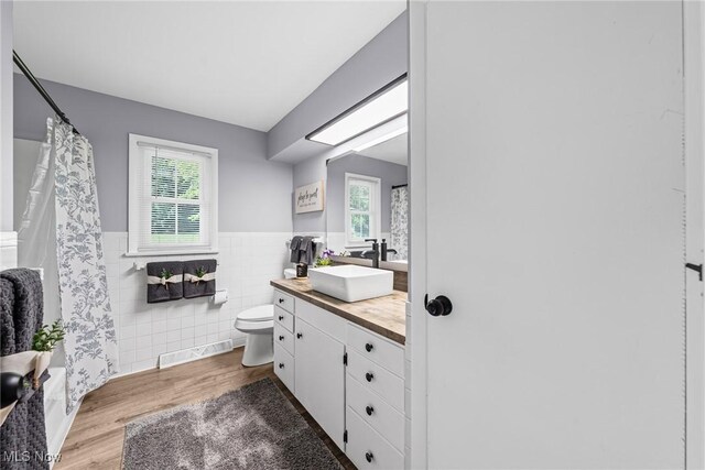 321 Stuart St NW, Lehigh Twp, OH 44646 - full bath with vanity, tile walls, wainscoting, healthy amount of natural light, and wood finished floors