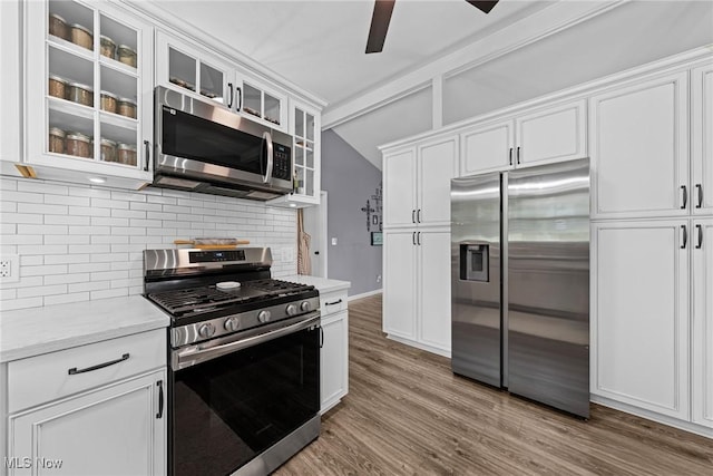 321 Stuart St NW, Lehigh Twp, OH 44646 - kitchen with appliances with stainless steel finishes, decorative backsplash, vaulted ceiling, white cabinetry, and ceiling fan