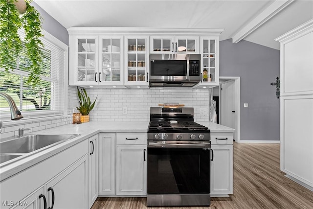 321 Stuart St NW, Lehigh Twp, OH 44646 - kitchen with appliances with stainless steel finishes, tasteful backsplash, white cabinetry, light countertops, and wood finished floors