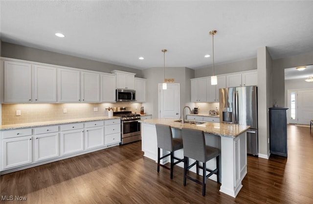 13861 Woodhawk Dr, Strongsville, OH 44136 - kitchen featuring appliances with stainless steel finishes, white cabinetry, backsplash, a breakfast bar area, and dark wood finished floors