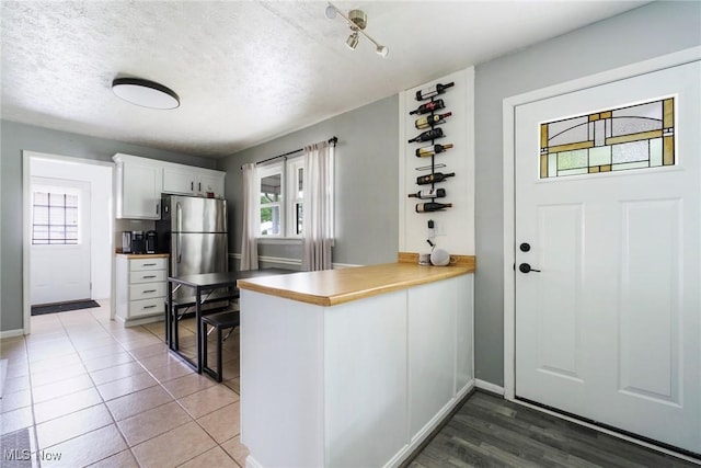 5672 Stanford Ave, Youngstown, OH 44515 - kitchen featuring freestanding refrigerator, white cabinetry, a peninsula, and a textured ceiling
