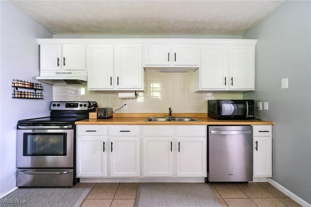 5672 Stanford Ave, Youngstown, OH 44515 - kitchen featuring appliances with stainless steel finishes, under cabinet range hood, light tile patterned floors, white cabinetry, and a textured ceiling