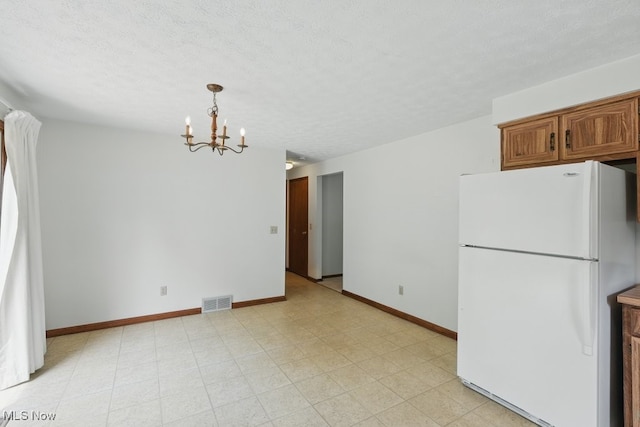 450 S Walnut St, Ravenna, OH 44266 - kitchen with freestanding refrigerator, a chandelier, a textured ceiling, brown cabinetry, and hanging light fixtures