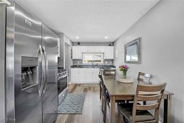 233 E 305th St, Willowick, OH 44095 - kitchen with appliances with stainless steel finishes, light wood-style flooring, white cabinetry, a textured ceiling, and dark countertops