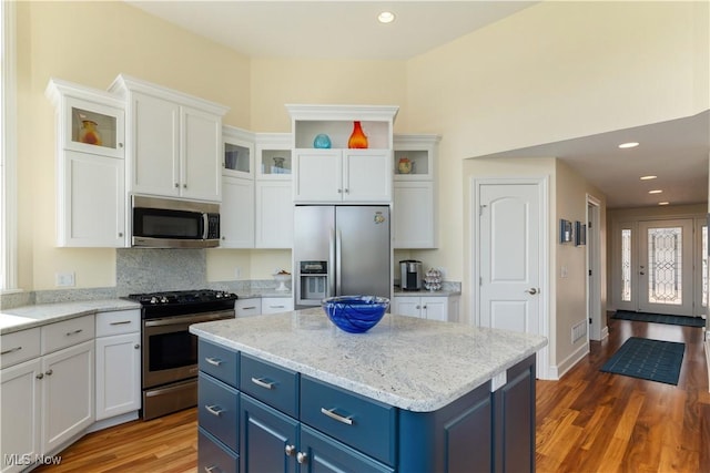 30 E Mohawk Dr, Malvern, OH 44644 - kitchen with stainless steel appliances, blue cabinetry, white cabinets, wood finished floors, and a kitchen island