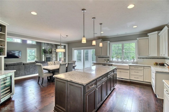 3179 Merion Ct, Westlake, OH 44145 - kitchen featuring beverage cooler, dark brown cabinets, ornamental molding, light stone counters, and open floor plan