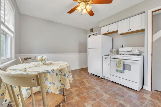 4465 W 156th St, Cleveland, OH 44135 - kitchen with white appliances, stone finish floors, ceiling fan, white cabinetry, and a wainscoted wall