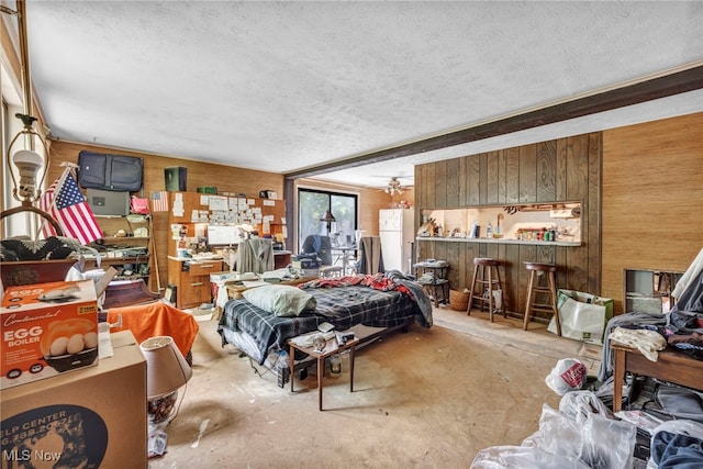 552 Turney Rd Unit A, Bedford, OH 44146 - bedroom with wood walls, unfinished concrete floors, a textured ceiling, and freestanding refrigerator