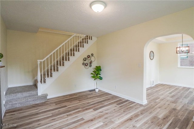 1967 Tonawanda Ave, Akron, OH 44305 - empty room with wood finished floors, stairway, arched walkways, a chandelier, and a textured ceiling