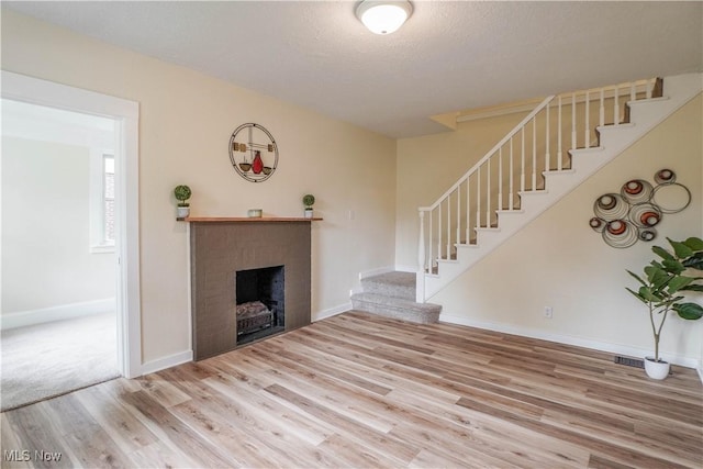 1967 Tonawanda Ave, Akron, OH 44305 - unfurnished living room featuring stairway, wood finished floors, a fireplace, and a textured ceiling