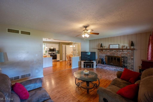 106 Wedgewood Dr, Parkersburg, WV 26104 - living area featuring a textured ceiling, a ceiling fan, light wood-style floors, and a fireplace