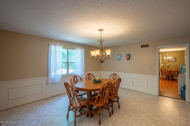 106 Wedgewood Dr, Parkersburg, WV 26104 - dining area featuring a chandelier, light floors, wainscoting, a textured ceiling, and a decorative wall