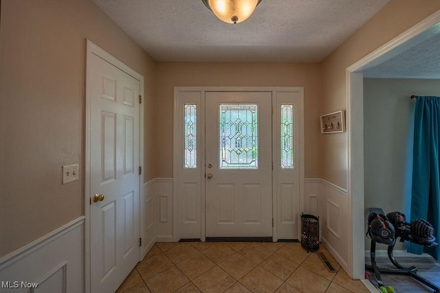 106 Wedgewood Dr, Parkersburg, WV 26104 - foyer entrance featuring a textured ceiling, a wainscoted wall, light tile patterned flooring, and a decorative wall