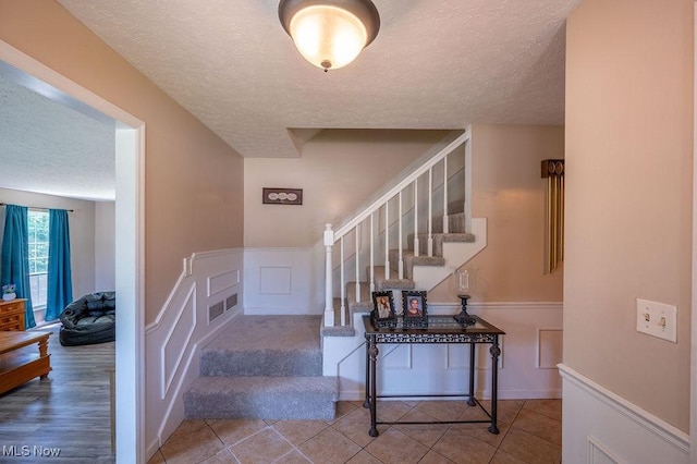 106 Wedgewood Dr, Parkersburg, WV 26104 - stairs featuring a textured ceiling, wainscoting, and a decorative wall