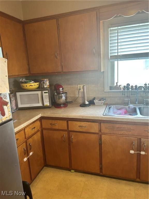 7438 Westview Dr, Youngstown, OH 44512 - kitchen with white microwave, light countertops, decorative backsplash, brown cabinetry, and freestanding refrigerator