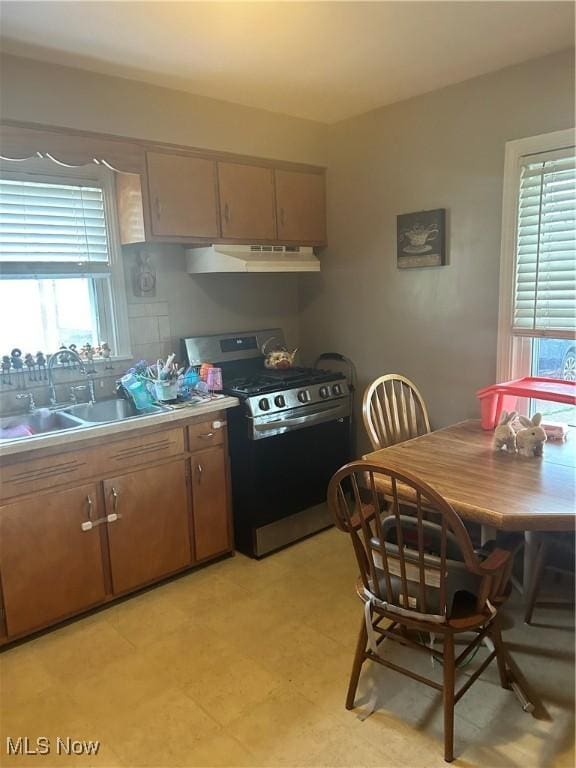 7438 Westview Dr, Youngstown, OH 44512 - kitchen with stainless steel gas stove, under cabinet range hood, light countertops, and light flooring