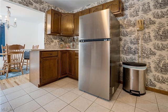 1701 19th Ave, Parkersburg, WV 26101 - kitchen featuring freestanding refrigerator, a chandelier, light tile patterned floors, a peninsula, and wallpapered walls