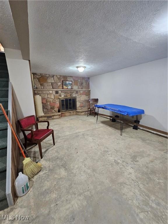 7261 Austin Dr, Mcconnelsville, OH 43756 - recreation room with concrete floors, a stone fireplace, and a textured ceiling
