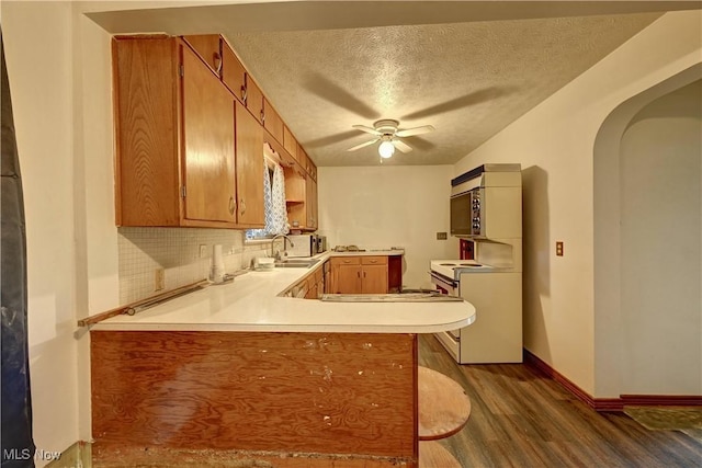 2335 Southway St SW, Massillon, OH 44646 - kitchen featuring a peninsula, arched walkways, dark wood-style floors, light countertops, and a ceiling fan