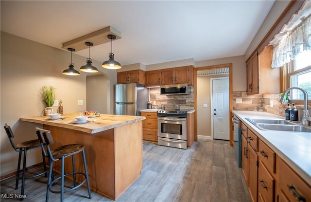 809 Mcdaniel Ave, Minerva, OH 44657 - kitchen with appliances with stainless steel finishes, a breakfast bar area, backsplash, wood finished floors, and pendant lighting