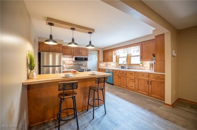 809 Mcdaniel Ave, Minerva, OH 44657 - kitchen featuring stainless steel appliances, a peninsula, decorative backsplash, a kitchen breakfast bar, and hanging light fixtures