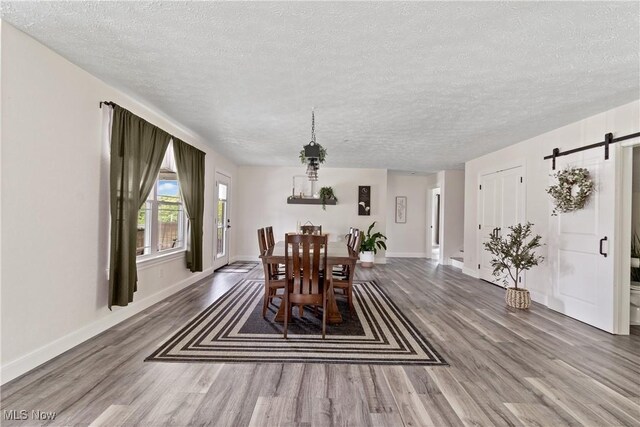 59301 Honeybee Rd, Senecaville, OH 43780 - dining area with a barn door, a textured ceiling, and wood finished floors
