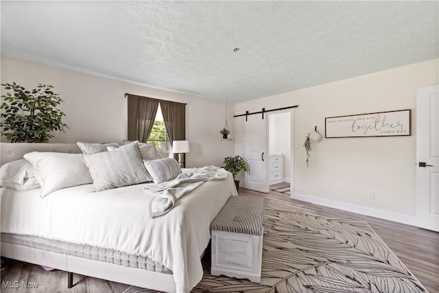 59301 Honeybee Rd, Senecaville, OH 43780 - bedroom with a barn door, wood finished floors, and a textured ceiling