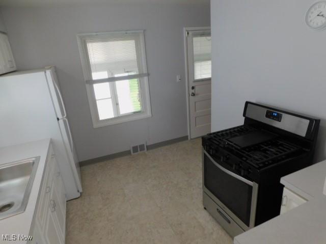 4139 W 144th St, Cleveland, OH 44135 - kitchen with gas stove, white cabinets, light countertops, and freestanding refrigerator