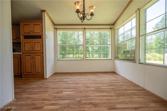 2500 Mcclintocksburg Rd, Deerfield, OH 44411 - unfurnished dining area with ornamental molding, a chandelier, plenty of natural light, light wood finished floors, and a textured ceiling