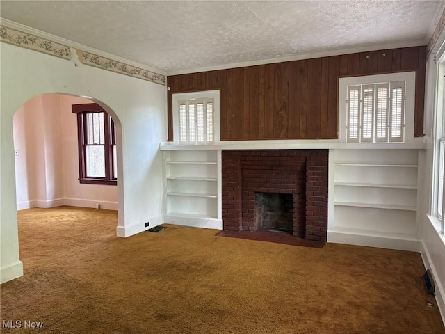 105 S Maple Hts, New Lexington, OH 43764 - unfurnished living room with crown molding, arched walkways, carpet floors, a textured ceiling, and plenty of natural light