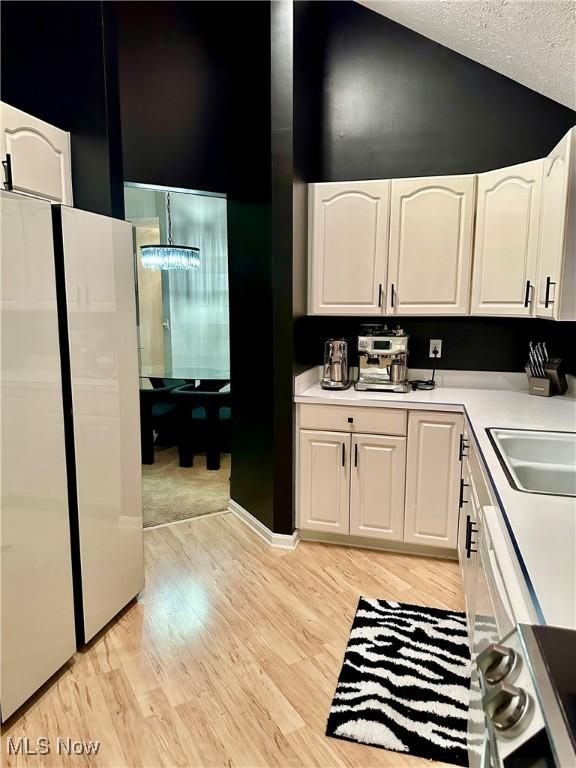 194 Vista Cir, North Olmsted, OH 44070 - kitchen with freestanding refrigerator, white cabinetry, light wood-type flooring, light countertops, and a textured ceiling
